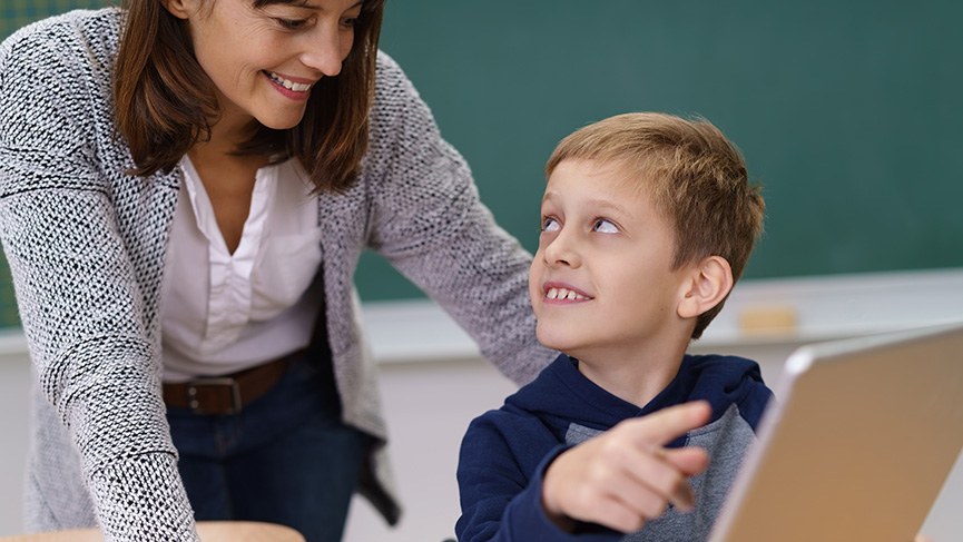 Schmuckbild: Klassenraum, Lehrerin hilft Schüler