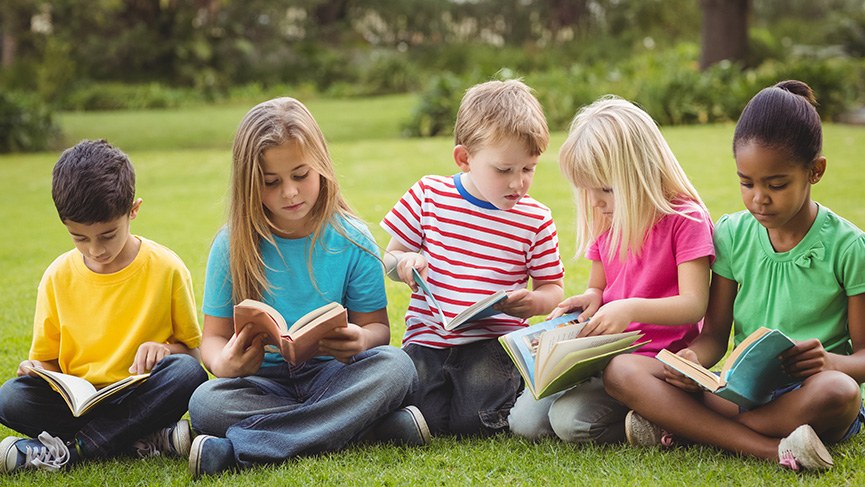 Schmuckbild: Kinder lesen auf einer Wiese