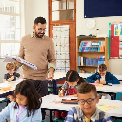 Lehrer mit Schulkindern am Laptop